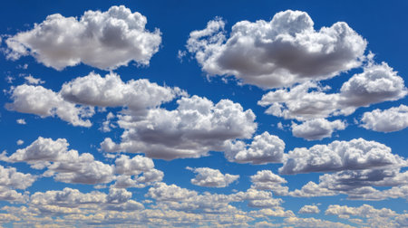 A collection of white, puffy cumulus clouds scattered across a clear, bright blue sky, suggesting a beautiful day.の素材