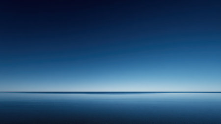 A minimalist landscape featuring a sharp, clean horizon line dividing a deep blue sky from a reflective, dark blue body of water.の素材