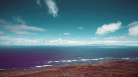 A breathtaking view of the ocean meeting the horizon under a dynamic sky with scattered clouds.の素材