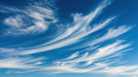 Beautiful wispy cirrus clouds drift across a clear, bright blue sky, creating a dynamic and serene natural landscape.の素材