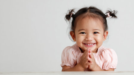 a cute young girl with pigtails smiles sweetly while wearing a pink shirt in a studio setting with a plain white background. She looks adorableの素材