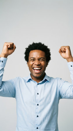 Portrait of a happy young african american man celebrating success isolated over gray backgroundの素材