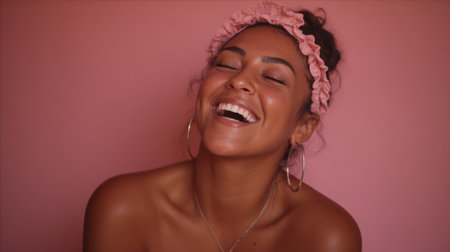 A radiant woman with dark skin and curly hair laughs heartily, her eyes closed in pure joy. She wears a pink ruffled headband and hoop earrings, her shoulders bare.の素材