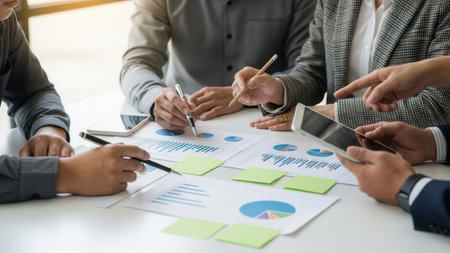 Group of business people meeting and discussing the charts and graphs showing the results of their successful teamwork.の素材