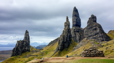 The iconic Old Man of Storr rock formations rise from the green landscape of the Isle of Skye under a dramatic cloudy sky in the Scottish Highlands.の素材