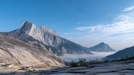 A breathtaking panoramic view of a rugged mountain landscape with smooth granite slopes in the foreground and peaks emerging from a sea of clouds in the valley below.の素材