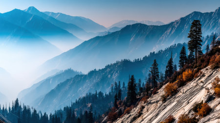 A breathtaking view of layered mountain ranges covered in a blue haze. Pine trees and rocky slopes are visible in the foreground, creating a sense of depth and tranquility.の素材