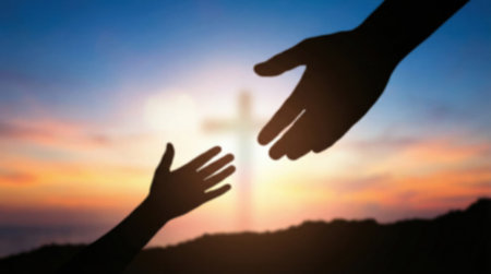 A silhouette of a helping hand reaching for another against a sunset sky with a glowing cross, symbolizing Gods love, salvation, faith, hope, and divine assistance.の素材