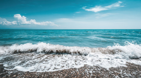 Idyllic coastal landscape featuring a gentle ocean wave with white foam lapping at the shore. A tranquil and relaxing nature background for travel concepts.の素材