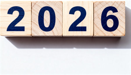 Wooden cubes with dark blue numbers spelling out 2026. The blocks are on a clean white surface with a slight shadow, symbolizing the new year and future planning.の素材