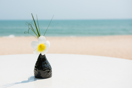 Flower in the vase are placed on the table near beach.の写真素材