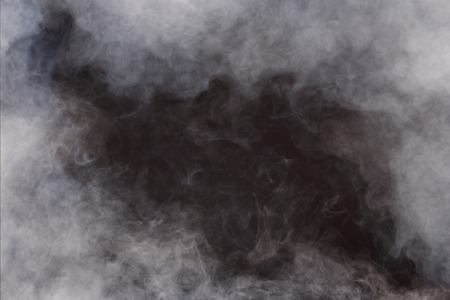 Dense Fluffy Puffs of White Smoke and Fog on Black Background, Abstract Smoke Clouds, All Movement Blurred, intention out of focus, and high low exposure contrast, copy space for text logoの写真素材