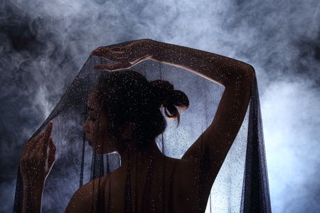 Ghost Story Smoking Tan Skin Asian Woman black hair dark lip with Dense Fluffy Puffs of White Smoke and Fog on dark Background, Abstract Smoke Clouds, and under low exposure contrast, copy space for text logoの写真素材