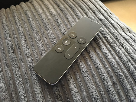 Black Smart Remote Control Sat On Grey Sofa
