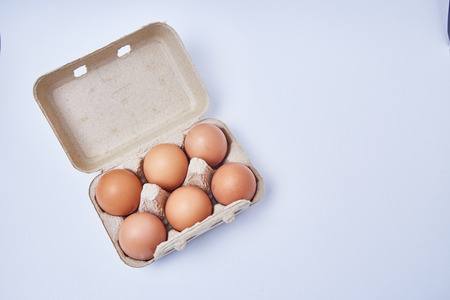 Six eggs in paper box on white backgroundの写真素材
