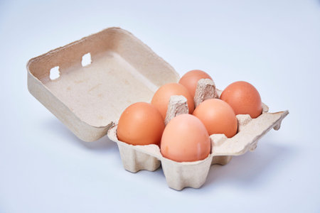 Six eggs in paper box on white background