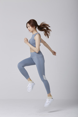 Selective motion focus of Asian girl wear exercise suit pose running in studio