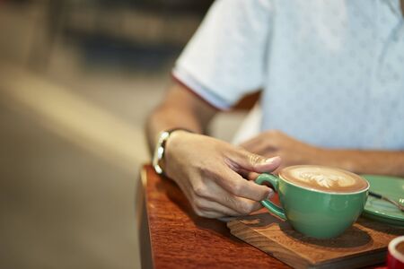 Colorful cup of coffee with hand holdingの写真素材