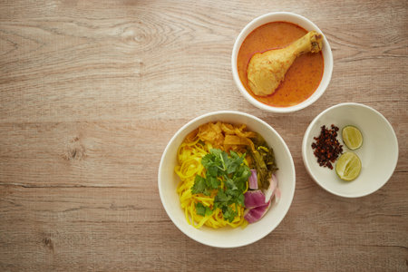 Top view of Noodles with chicken and curry in white bowl on wooden background, Khao soi a famous northern Thai foodの写真素材