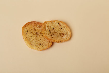 Two pieces of toasted bread on beige background, top view