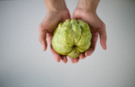 Imperfect fruit in hand on white background with copy spaceの写真素材