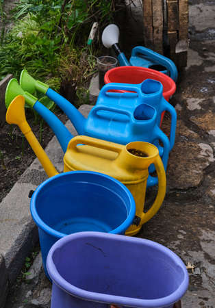 watering cans of different colors for watering flower beds and bedsの写真素材