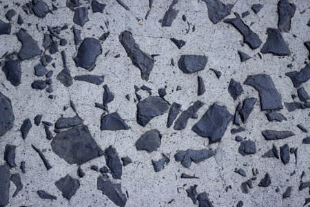 A concrete texture with embedded black rocks の写真素材