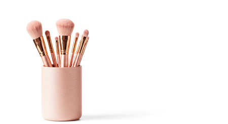 Makeup brushes in a pink cup on a white background. Copy space.の素材