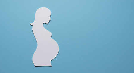 Pregnant woman silhouette made of paper on blue background, copy spaceの素材