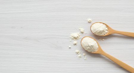 Flour in wooden spoons on white wooden table, top viewの素材