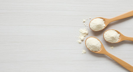 Coconut flour in wooden spoons on white wooden background.の素材