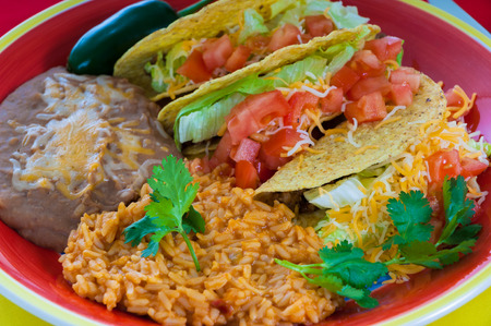 A plate of Mexican food with beans, rice and tacosの写真素材