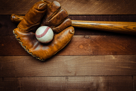 A group of vintage baseball equipment, bats, gloves, baseballs on wooden backgroundの写真素材