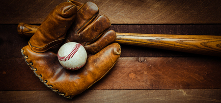 A group of vintage baseball equipment, bats, gloves, baseballs on wooden backgroundの写真素材