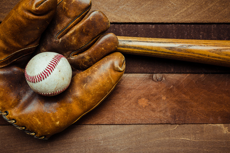 A group of vintage baseball equipment, bats, gloves, baseballs on wooden backgroundの写真素材