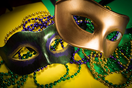 Two Mardi Gras mask with colorful beads on a yellow backgroundの写真素材