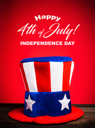 A felt colorful Uncle Sam hat on red background with Happy July 4th greetingの写真素材