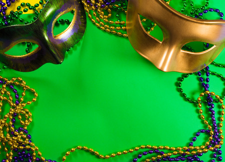 Two Mardi Gras mask with colorful beads on a green backgroundの写真素材