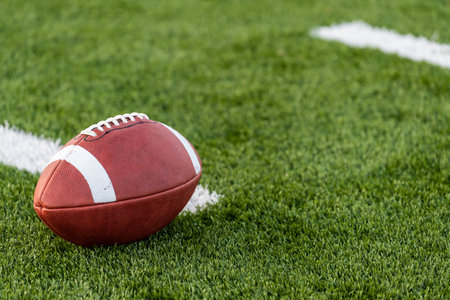 A brown leather american football on a green playing field