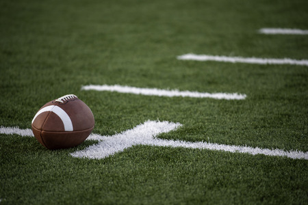 A brown leather american football on a green playing fieldの写真素材