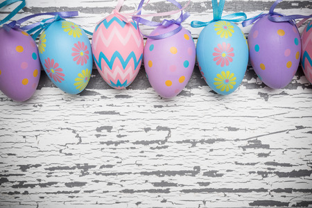 A group of pastel colored Easter eggs on a white, aged wooden background with copy space.の写真素材