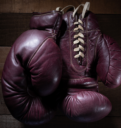 Pair of vintage, antique boxing gloves on a brown, slat wooden backgroundの写真素材