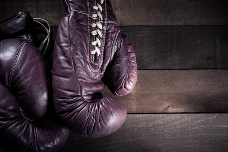 Pair of vintage, antique boxing gloves on a brown, slat wooden backgroundの写真素材