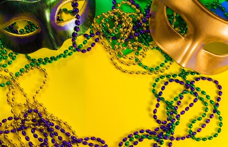 Two Mardi Gras mask with colorful beads on a yellow backgroundの写真素材