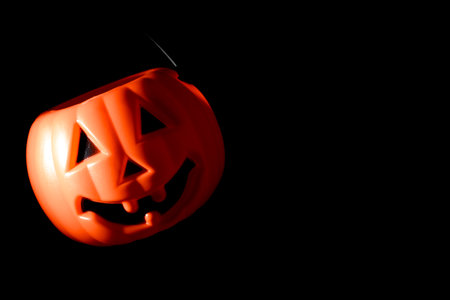 Halloween jack-o-lantern candy buckets or pail on orange backgroundの写真素材