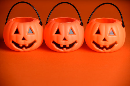 Halloween jack-o-lantern candy buckets or pail on orange backgroundの写真素材
