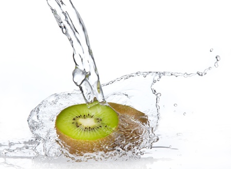 Fresh pieces of kiwi in water splash, isolated on white backgroundの写真素材