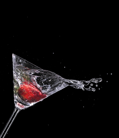 Martini drink splashing out of glass, isolated on black backgroundの写真素材