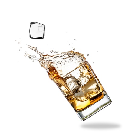 Whiskey splashing out of glass, isolated on white backgroundの写真素材