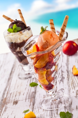 Delicious ice cream cups on wooden table and blur beach on backgroundの写真素材